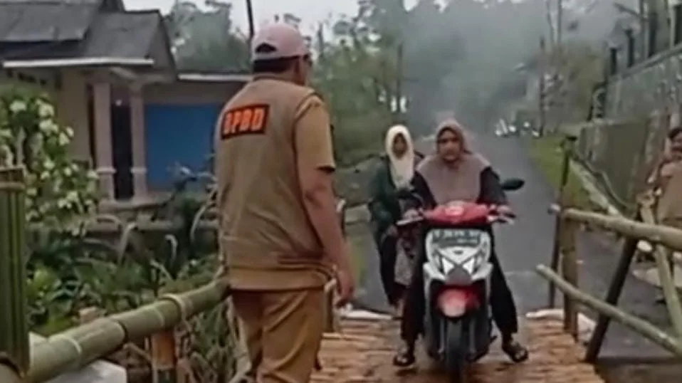 Masyarakat Kecamatan Pulosari sedang melintas di jembatan darurat menggunakan sepeda motor.