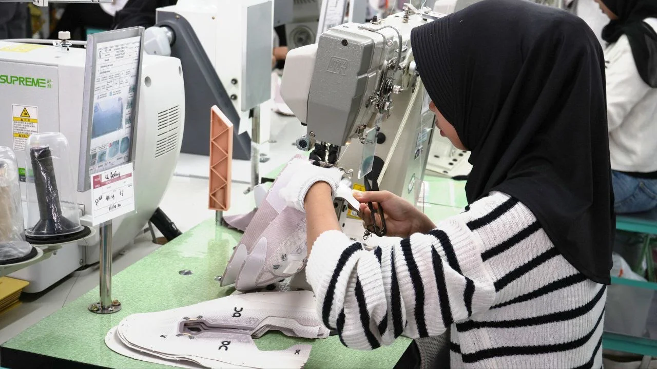 Salah satu pekerja di perusahaan swasta sedang memproduksi sepatu.