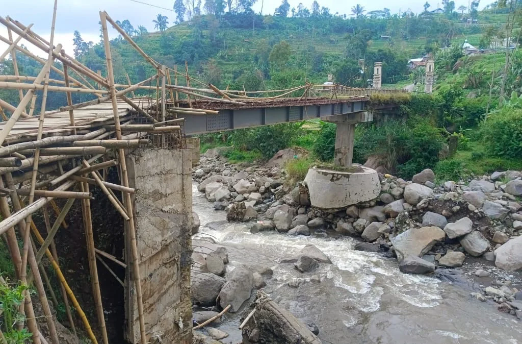 Pengendara motor melintasi Jembatan Glempang di Desa Kaligiri, Sirampog, Brebes, yang masih menggunakan konstruksi bambu karena pembangunannya belum dilanjutkan.