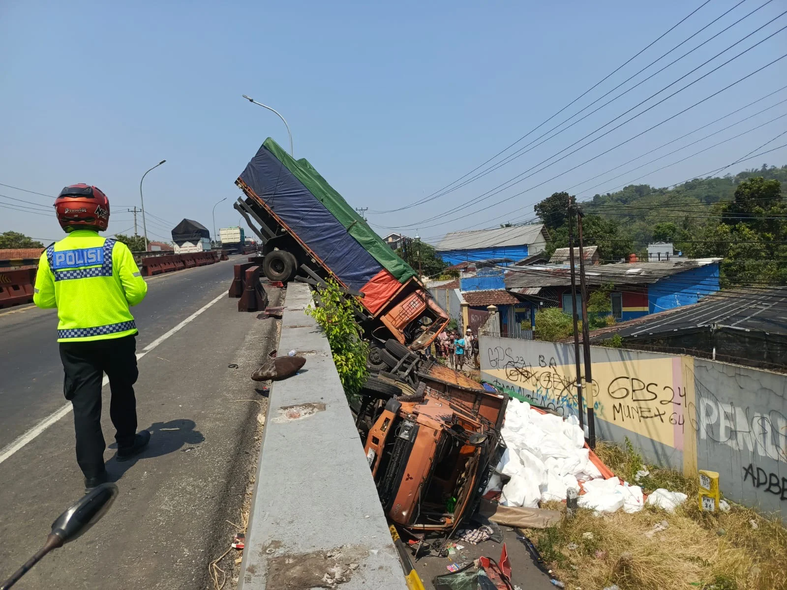 Dua truk Fuso terjun dari Flyover Kretek, Kecamatan Paguyangan, Kabupaten Brebes, usai terlibat kecelakaan beruntun yang diduga dipicu rem blong. Salah satu truk tampak masih menggantung di bibir flyover, sementara truk lainnya terguling di jalan bawah dengan muatan tisu berserakan.
