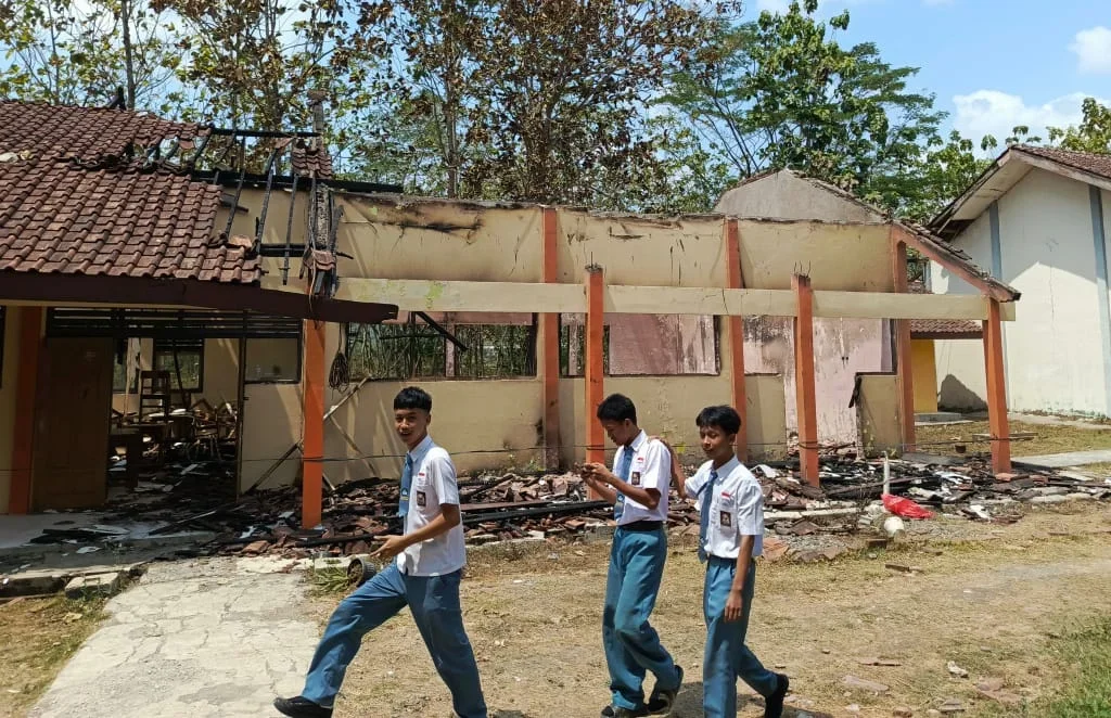 Sejumlah siswa SMA Negeri 1 Bantarkawung melintas di depan bangunan kelas yang hangus terbakar di Desa Pangebatan, Kecamatan Bantarkawung, Brebes, Senin, 7 September 2026.